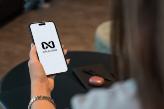 Person holding a smartphone with a logo on screen.