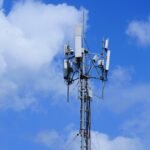 Cell tower with antennas against a cloudy blue sky