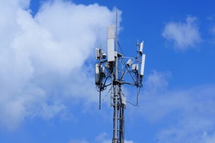 Cell tower with antennas against a cloudy blue sky
