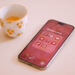 Smartphone with app icons next to a floral cup