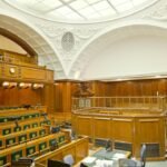 Empty ornate courtroom interior with wooden paneling and green seats